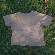 a t - shirt that is laying on the ground with grass in front of it