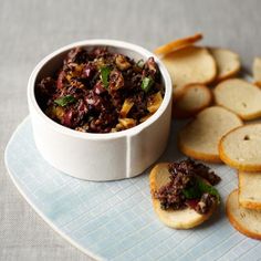 a bowl of food sitting on top of a blue plate next to sliced up bread