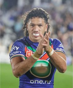 a rugby player with his hands in the air while holding a ball and making a hand gesture