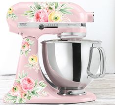 a pink mixer with flowers painted on it's side sitting on a wooden table