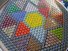 there is a plate made out of many different colored soda bottle caps on the table