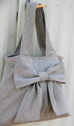 a gray and white bag with a bow on the front, hanging from a hook