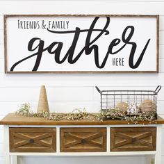 a wooden sign that says friends and family gather here on top of a white table