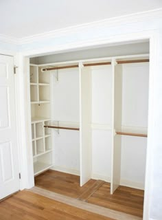 an empty closet with white walls and wooden floors