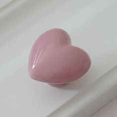 a pink heart shaped object sitting on top of a white counter next to a window