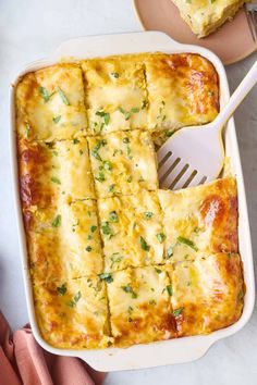 a casserole dish with cheese and parsley on the side next to a fork