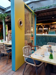 an outdoor dining area with wooden tables and wicker chairs, yellow walls and blue trim