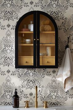 a bathroom sink under a mirror next to a wall papered with flowers and leaves