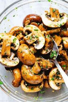 a glass bowl filled with mushrooms covered in parsley