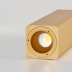 a wooden object with a white light on it's side and a gray background