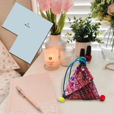 a white table topped with pink flowers next to a notepad and pen on top of it