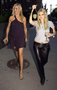 two beautiful women walking down the street holding wine bottles