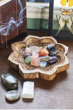 some rocks are sitting in a bowl on a table next to a butterfly and other items