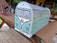 a blue and white bus shaped mailbox sitting on top of a wooden picnic table