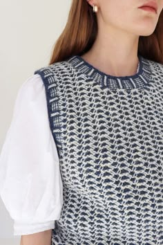 a woman with red hair wearing a white shirt and blue patterned dress, looking off to the side