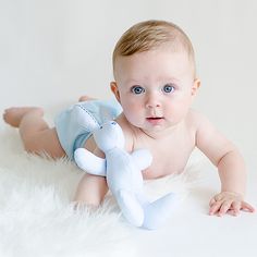 a baby laying on the floor with a stuffed animal