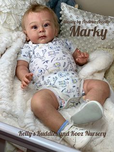 a baby laying in a crib next to a teddy bear and pillow with the caption mary's huddle and kooz nursery