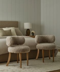 two sheepskin chairs sit in front of a bed