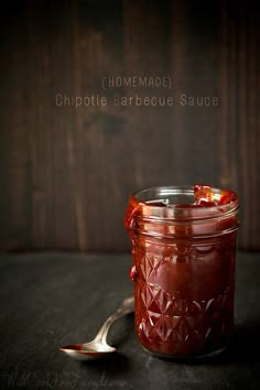 a spoon sitting next to a jar filled with barbecue sauce