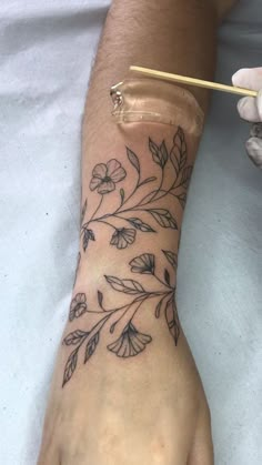 a person with a flower tattoo on their arm holding a toothbrush in one hand