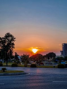 the sun is setting behind some buildings on the other side of the street in front of it