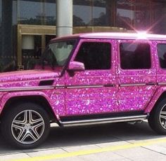 a pink and black jeep parked in front of a building with purple glitter on it