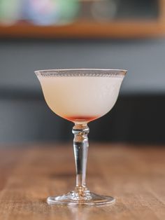 a glass filled with liquid sitting on top of a wooden table