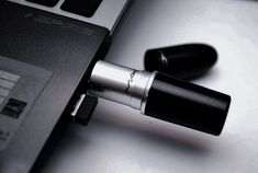 an open laptop computer sitting on top of a white table next to a black and silver pen