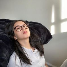 a woman wearing glasses is laying on a couch with her head resting on the pillow