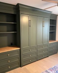 an empty room with green cupboards and drawers in the center, along with a rug on the floor