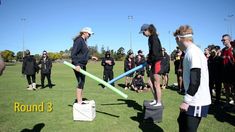 a group of people standing on top of a field holding baseball bat and buckets