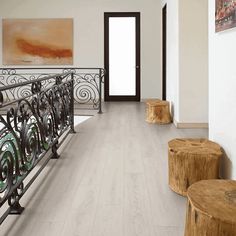 a hallway with white walls and wood flooring next to a wooden bench on the ground