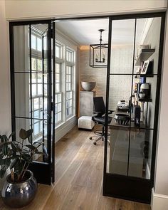 an office with glass walls and wooden flooring is seen through the door to another room