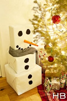 a snowman made out of boxes next to a christmas tree