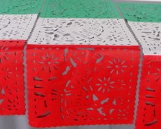 red and white table cloth with cut out designs on the top, sitting on a wooden table