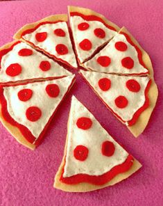 a pizza cut into four slices on a pink surface