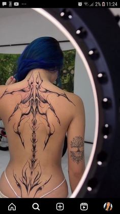 the back of a woman's body with tattoos on it