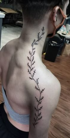 the back of a woman's neck is covered with small black flowers and leaves