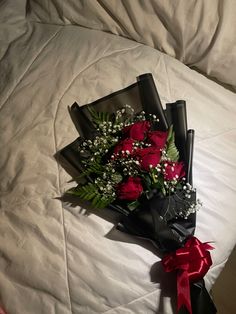 a bouquet of red roses sitting on top of a white bed sheet covered in sheets