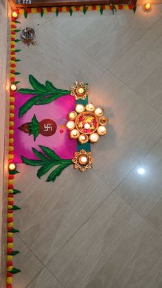 an overhead view of a decorated floor with lit candles and flowers on the ground for diwaling