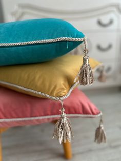 pillows with tassels are stacked on top of each other