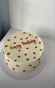 a white cake with red hearts on it and the words happy birthday written on top