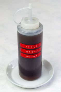 an empty bottle on top of a saucer with a red stripe around the bottom