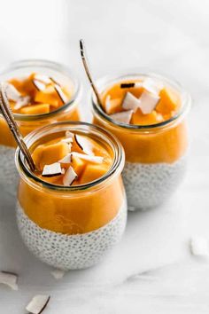 three jars filled with pudding and topped with marshmallows on a white surface