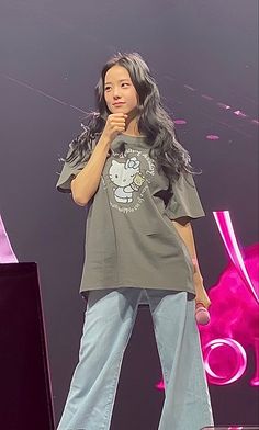 a woman standing on top of a stage with her hand up to her mouth and holding a microphone