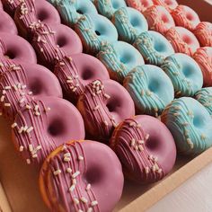 a box full of colorful donuts with sprinkles on them sitting on a table