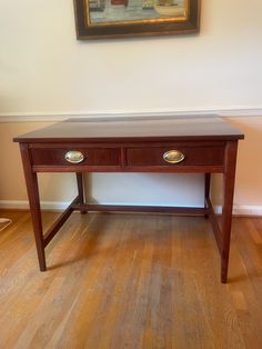 a wooden table with two drawers in front of a painting