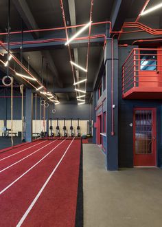 the inside of a gym with red and black walls, lights, and treading