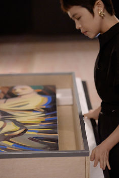 a woman looking at an art work on display