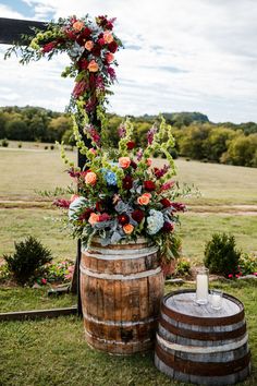 a wooden barrel with flowers on it sitting in the grass next to an old barrel